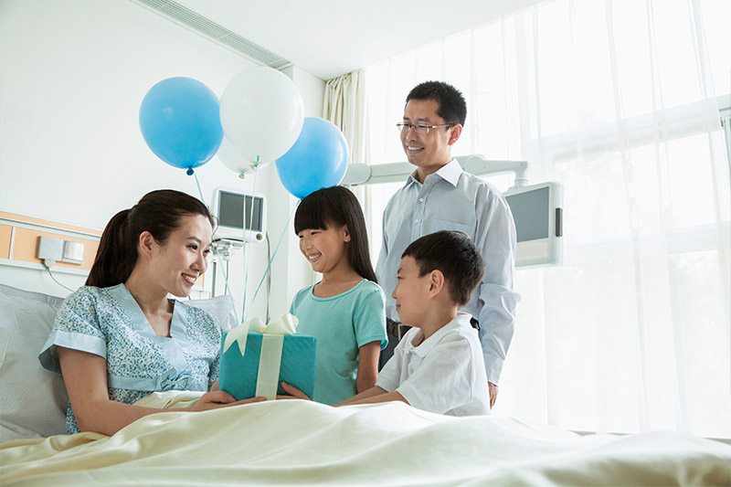 Family giving mom a gift in the hospital